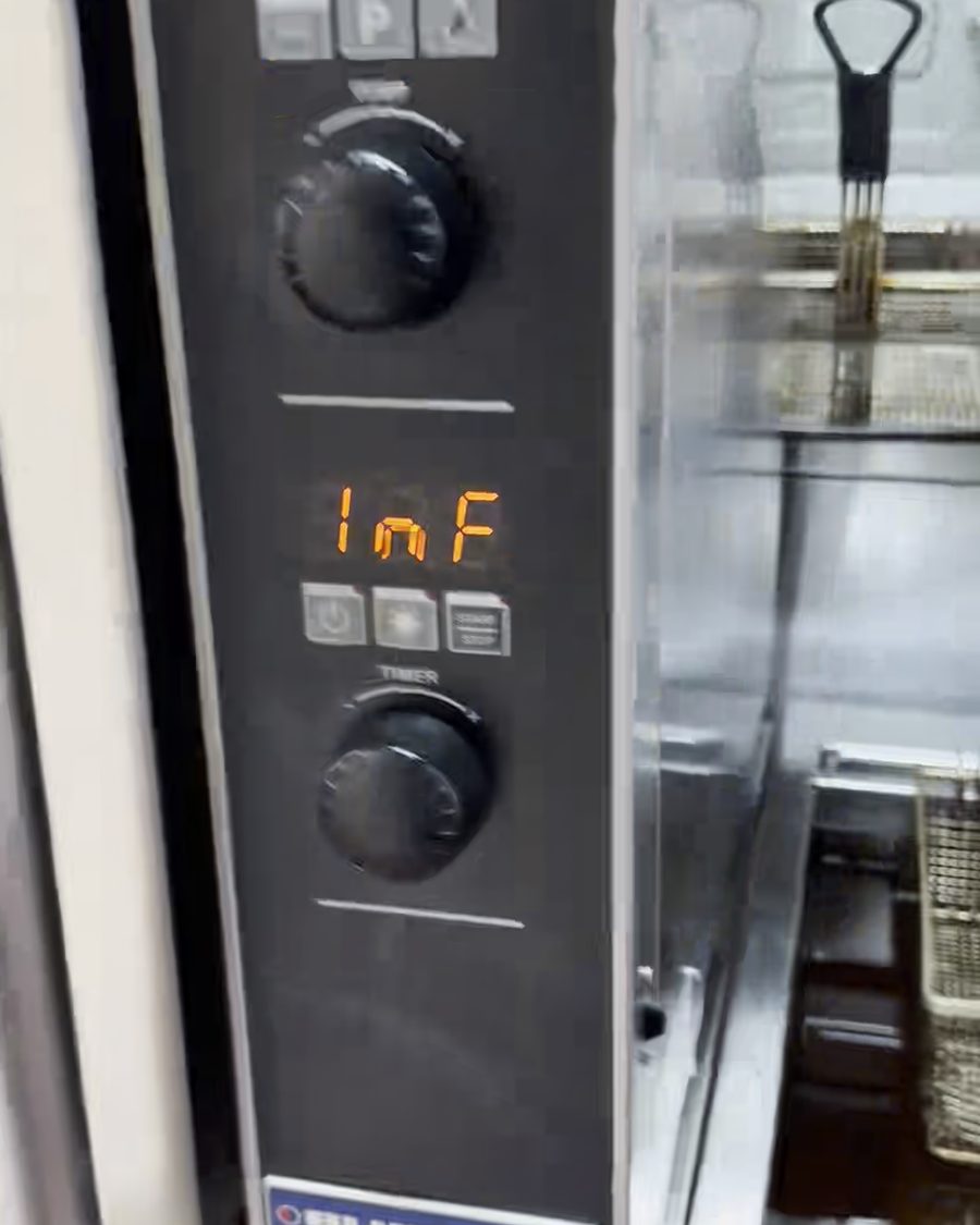 Control panel of a commercial oven with temperature and timer dials, beside a stainless steel fryer