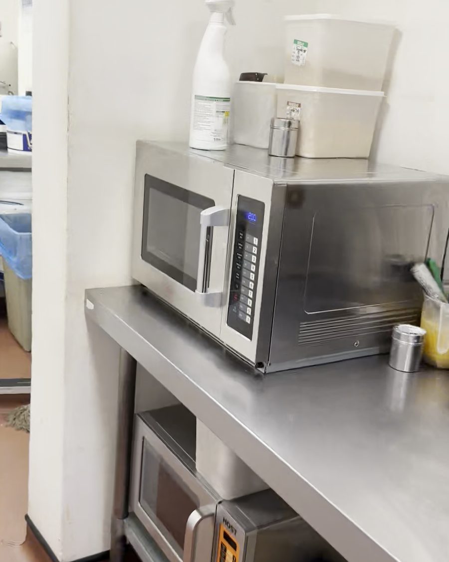 Stainless steel commercial microwave on a steel prep table in a commercial kitchen